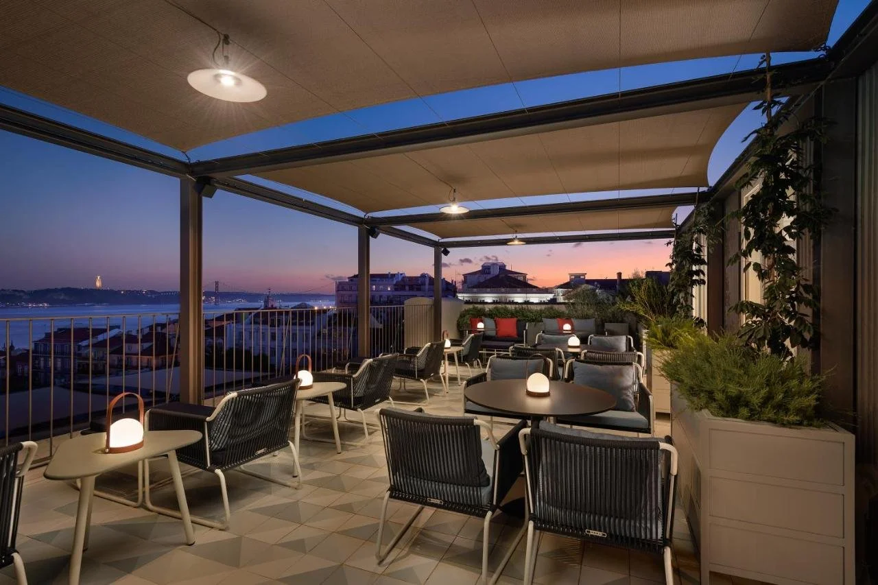 Bairro Alto Hotel Lisbon rooftop terrace at dusk with Ponte 25 de Abril, Tagus River and Christ the King at sunset
