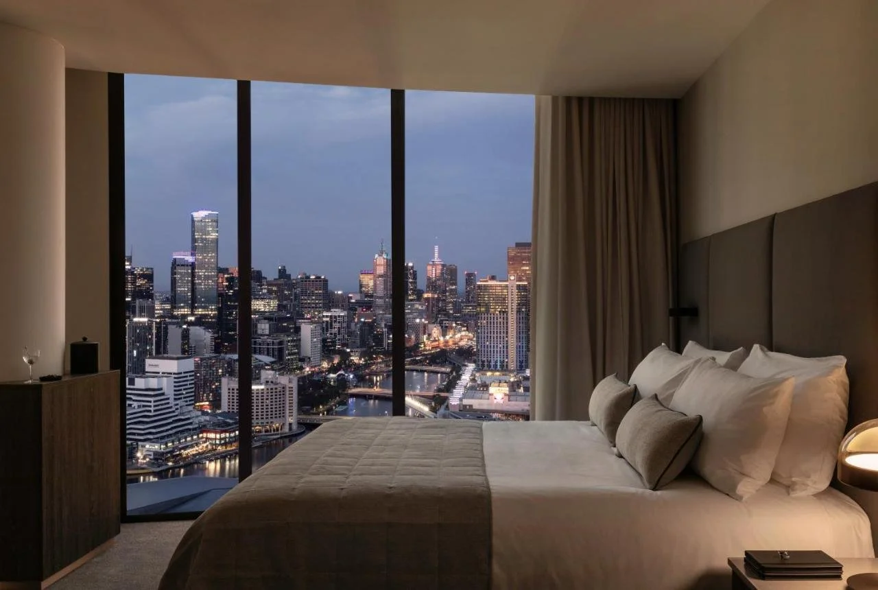 Oakwood Premier Melbourne hotel room at night with floor-to-ceiling window showing the Yarra River, Southbank, and full Melbourne CBD skyline