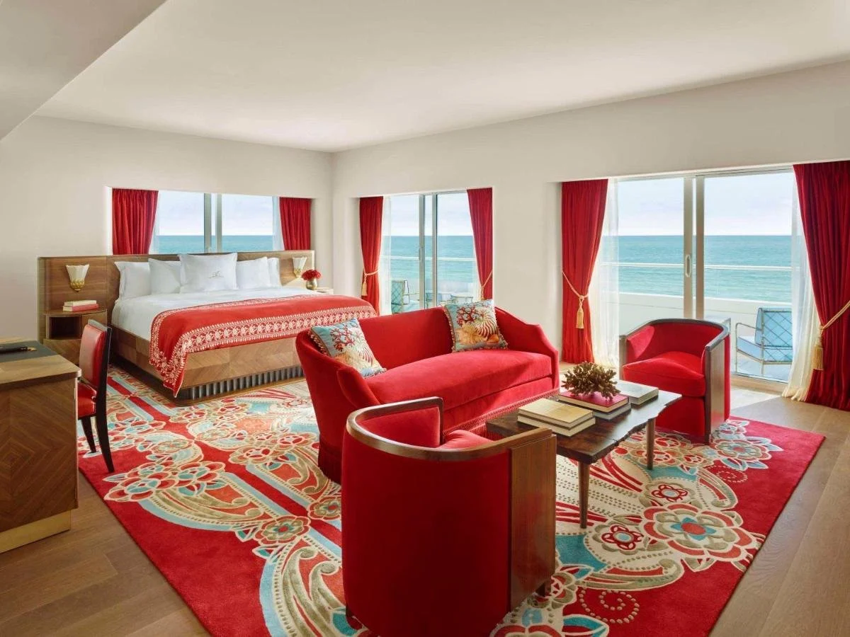 Faena Hotel Miami Beach oceanfront suite with red velvet furnishings, gold accents and panoramic Atlantic Ocean views through multiple windows