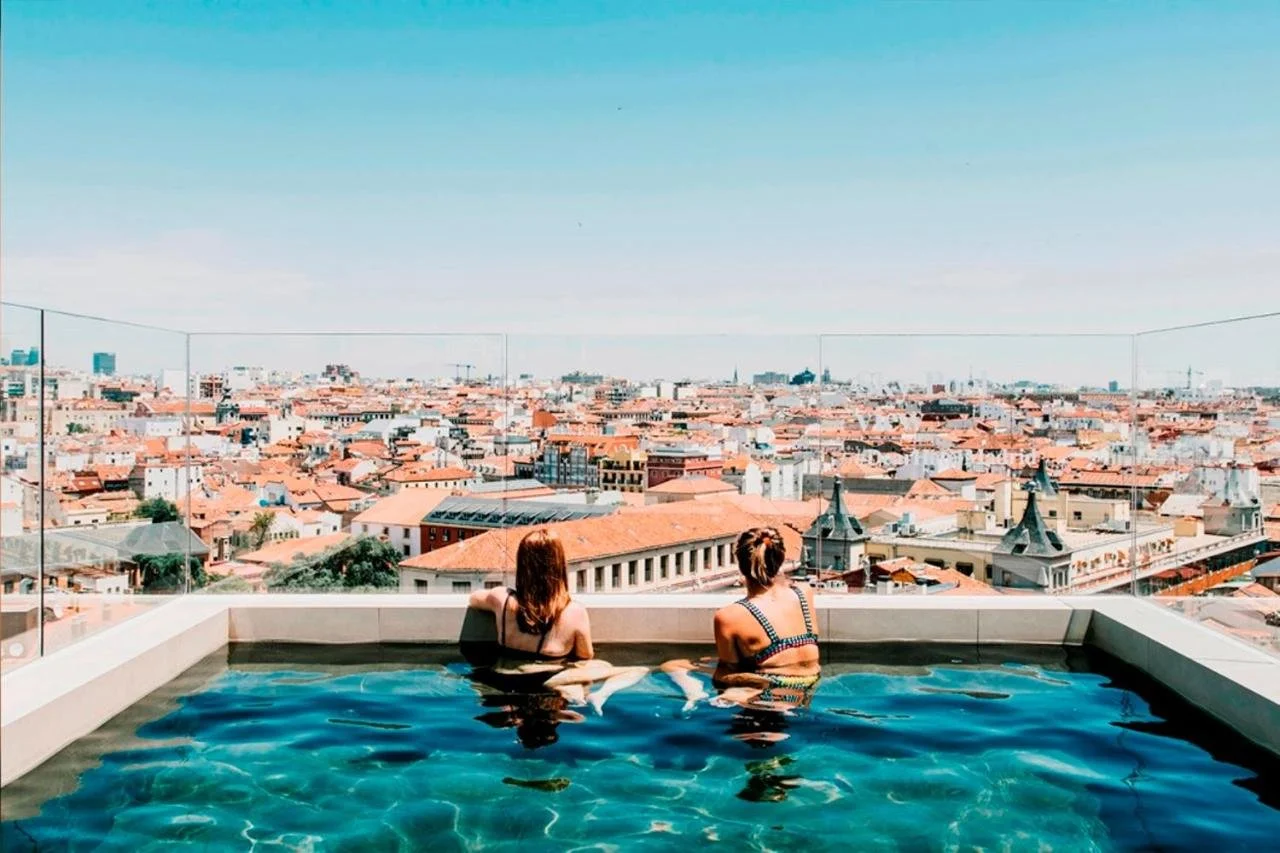 Dear Hotel Madrid rooftop Sky Pool with guests and panoramic view of Madrid city center rooftops and church spires
