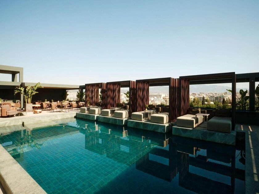 Radisson Blu Park Hotel Athens rooftop pool terrace with wooden-frame cabanas and Athens city panorama