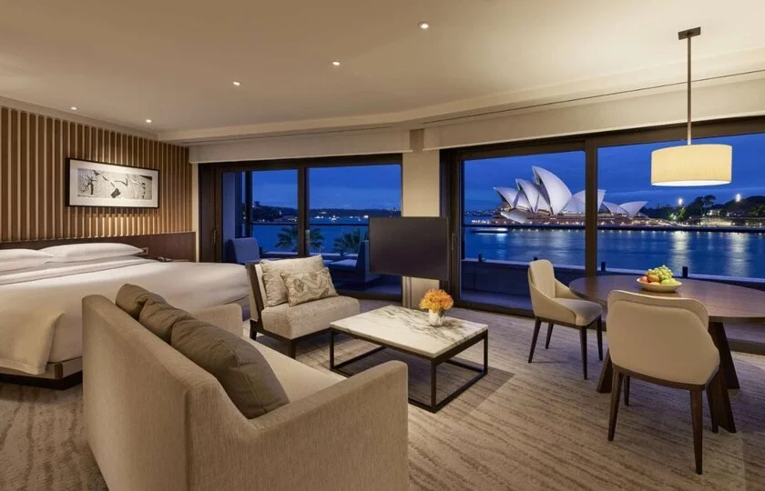 Park Hyatt Sydney suite living area with floor-to-ceiling windows framing the illuminated Opera House at night