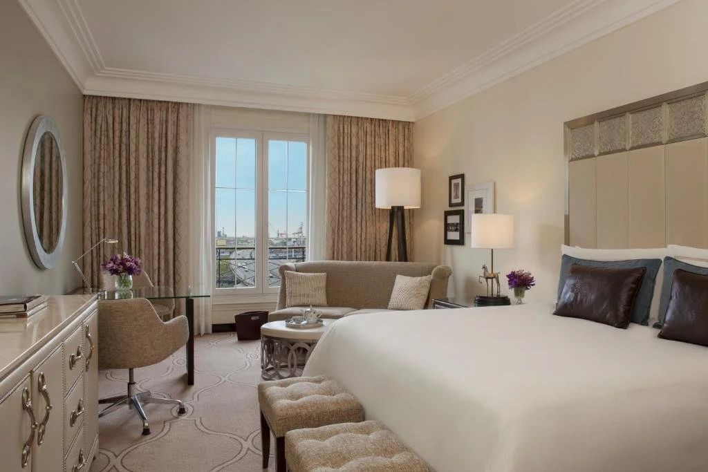 Four Seasons Hotel Buenos Aires classically furnished bedroom with tall window overlooking city rooftops and distant port area
