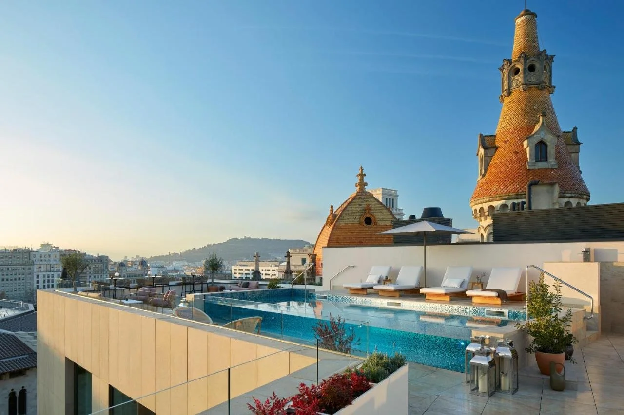 ME Barcelona rooftop pool at golden hour with Cases Antoni Rocamora Modernist tiled turrets and Eixample city skyline