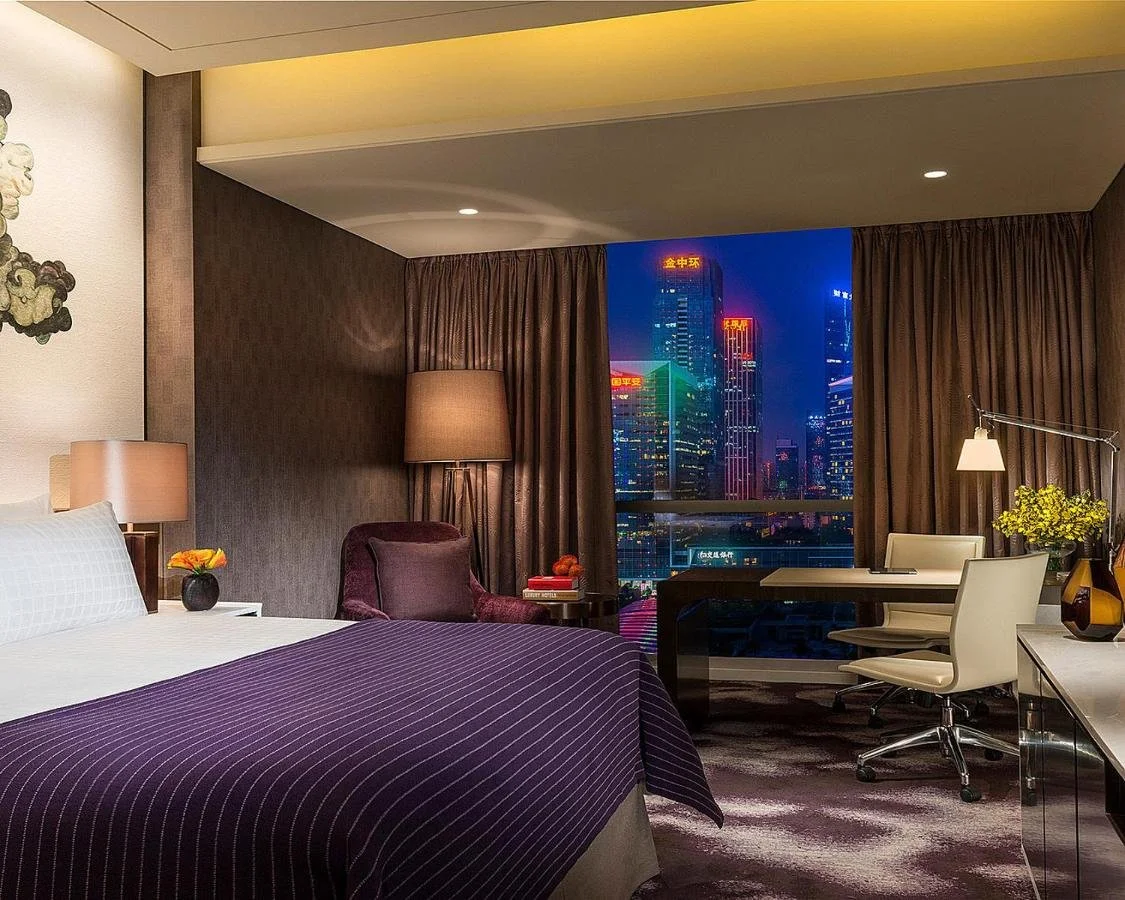 Four Seasons Hotel Shenzhen guestroom at night, floor-to-ceiling window framing the illuminated Futian skyline including the Ping An Finance Centre