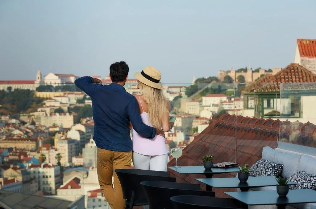 The Lumiares Hotel Spa Lisbon Lumi Rooftop terrace with couple at glass railing overlooking Bairro Alto rooftops and São Jorge Castle