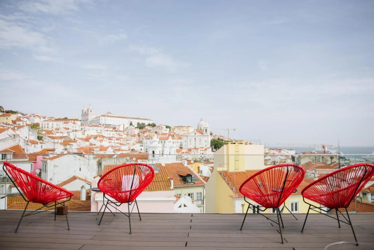 Memmo Alfama Design Hotels Lisbon rooftop terrace with red chairs overlooking Alfama rooftops, Church of São Vicente de Fora, Santa Engrácia dome and Tagus River