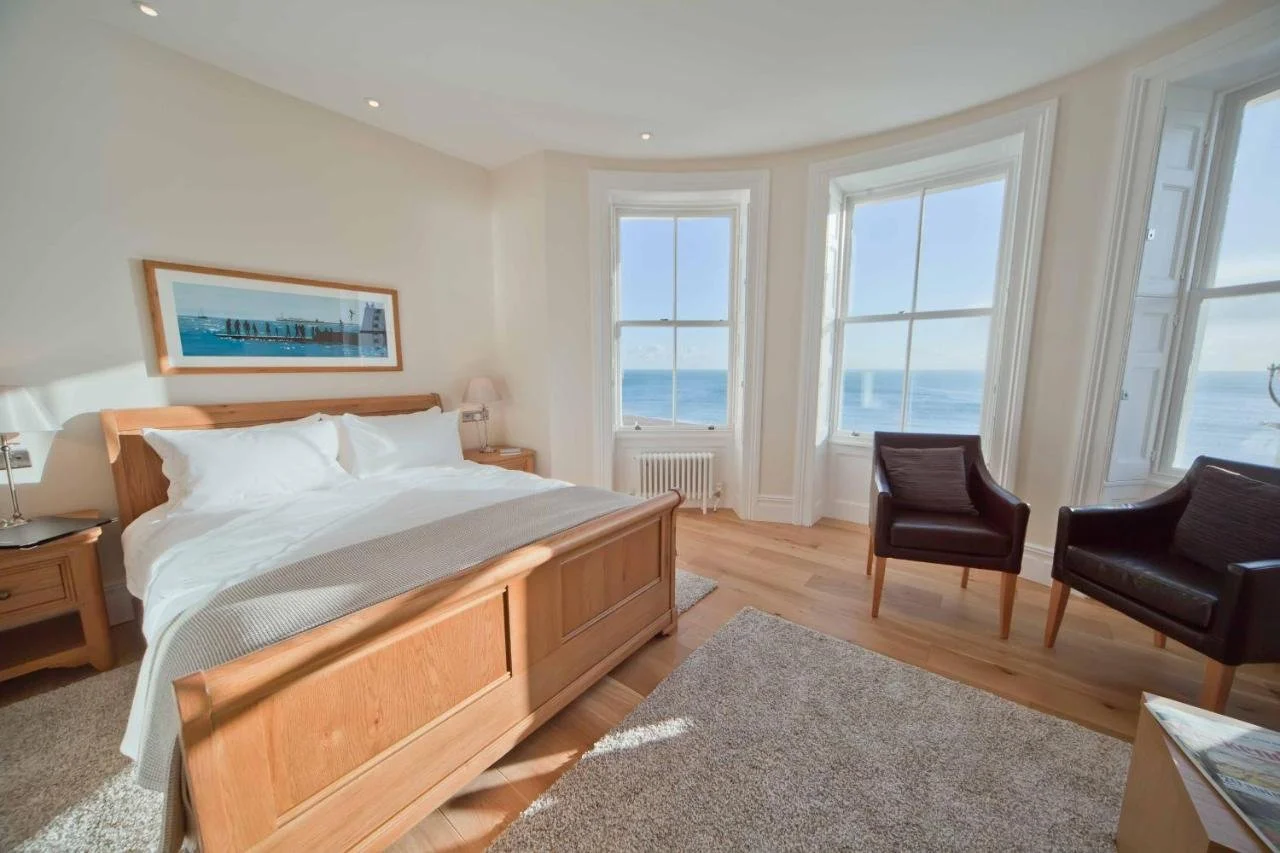 A Room With A View Brighton double bedroom with oak bed, hardwood floors, and two large sash bay windows overlooking the English Channel