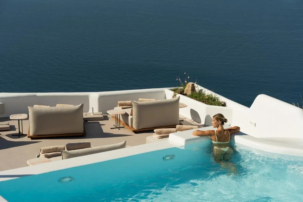 Canaves Ena Santorini infinity pool terrace with Aegean Sea view and outdoor lounge seating