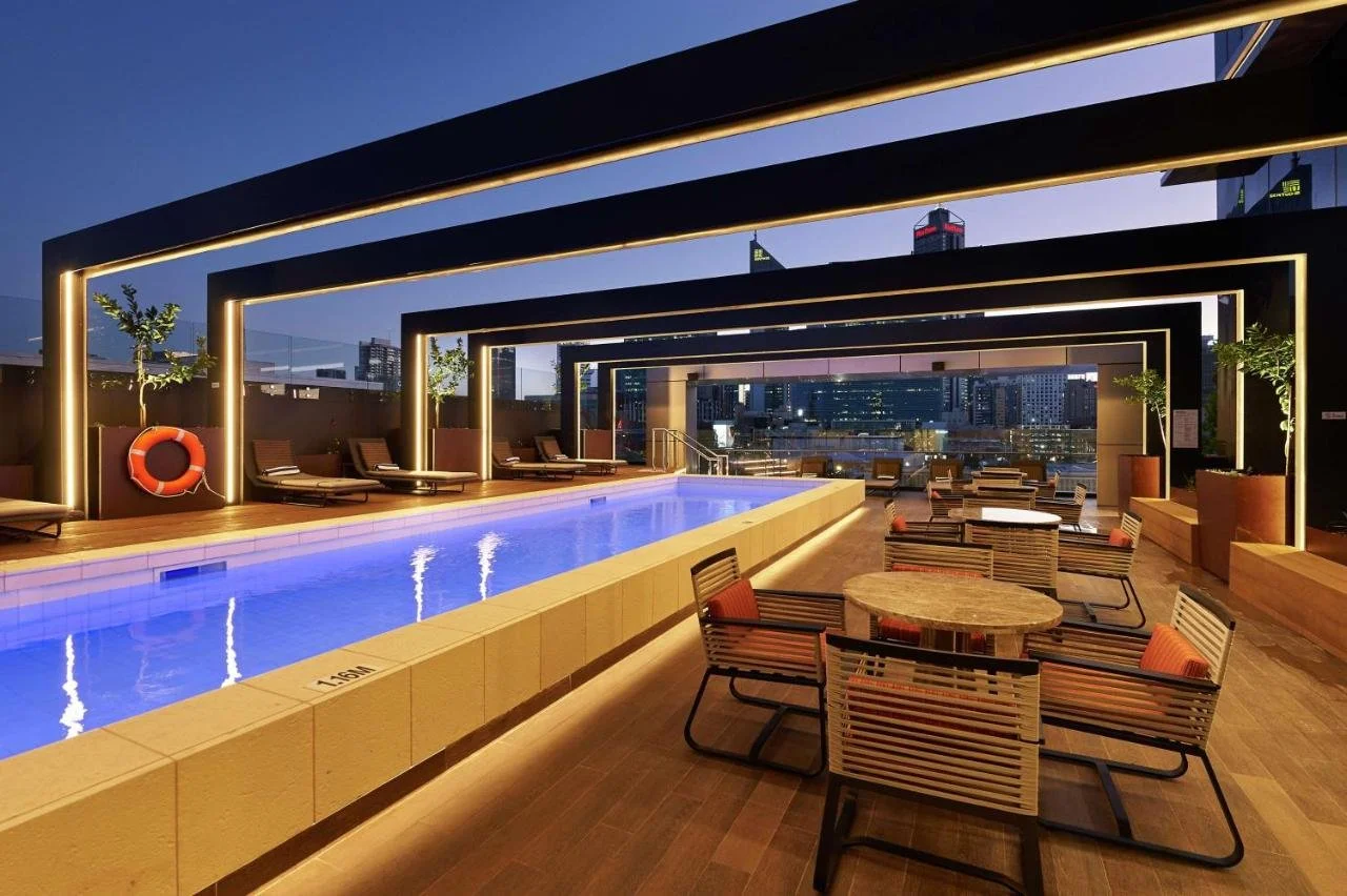 DoubleTree by Hilton Perth Northbridge rooftop pool at night with illuminated Perth CBD skyline