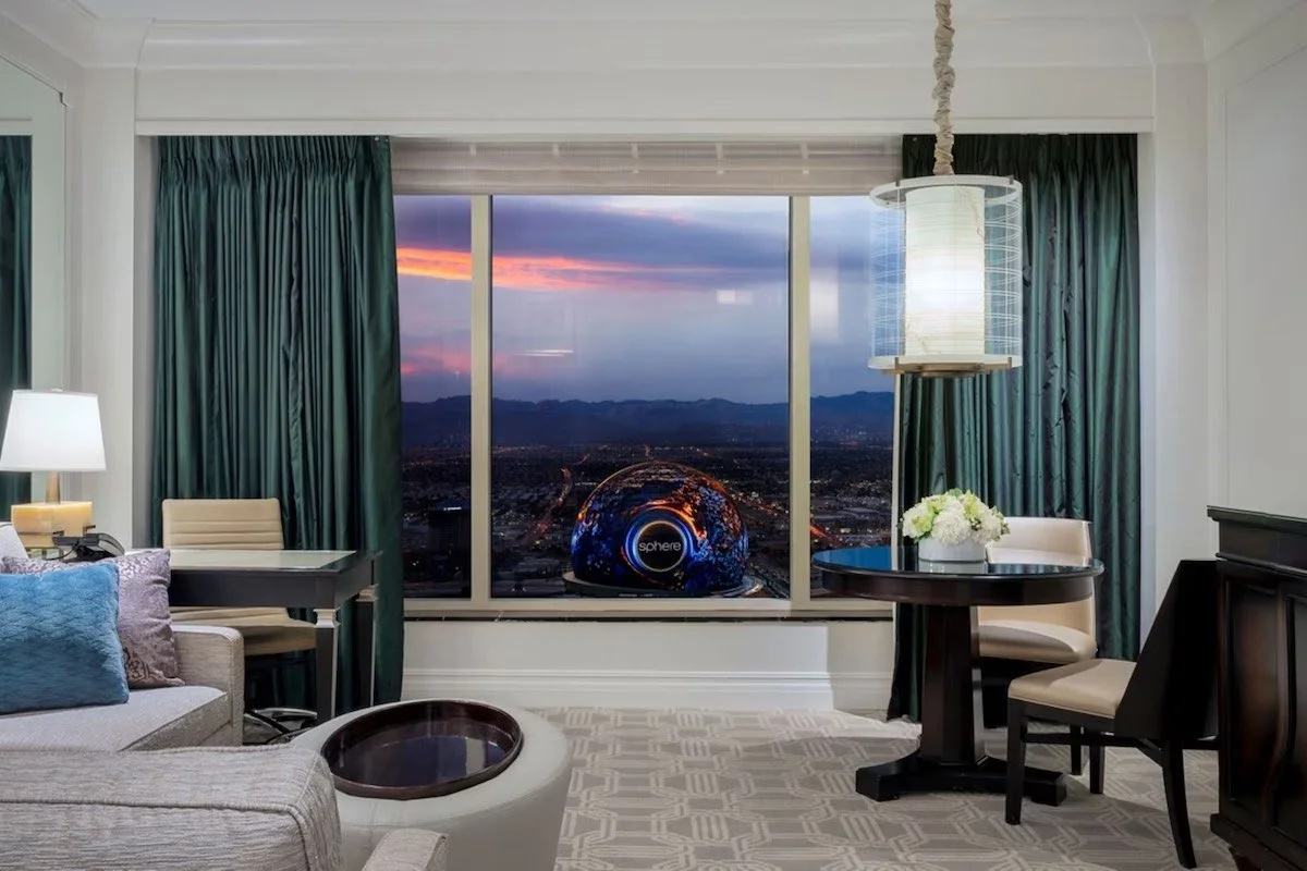 The Palazzo at The Venetian Las Vegas suite living room with floor-to-ceiling windows framing the illuminated Sphere and city lights at dusk