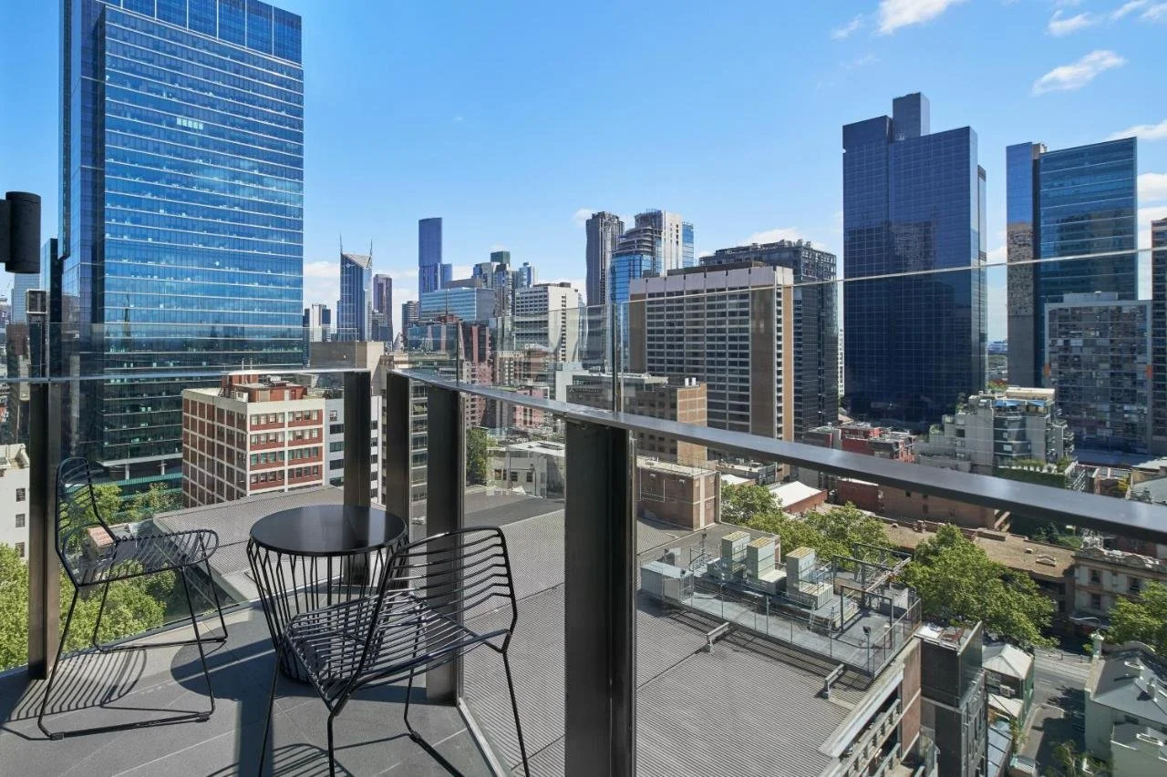Sheraton Melbourne Hotel upper-floor terrace balcony with table and chairs and view of Melbourne CBD skyscrapers