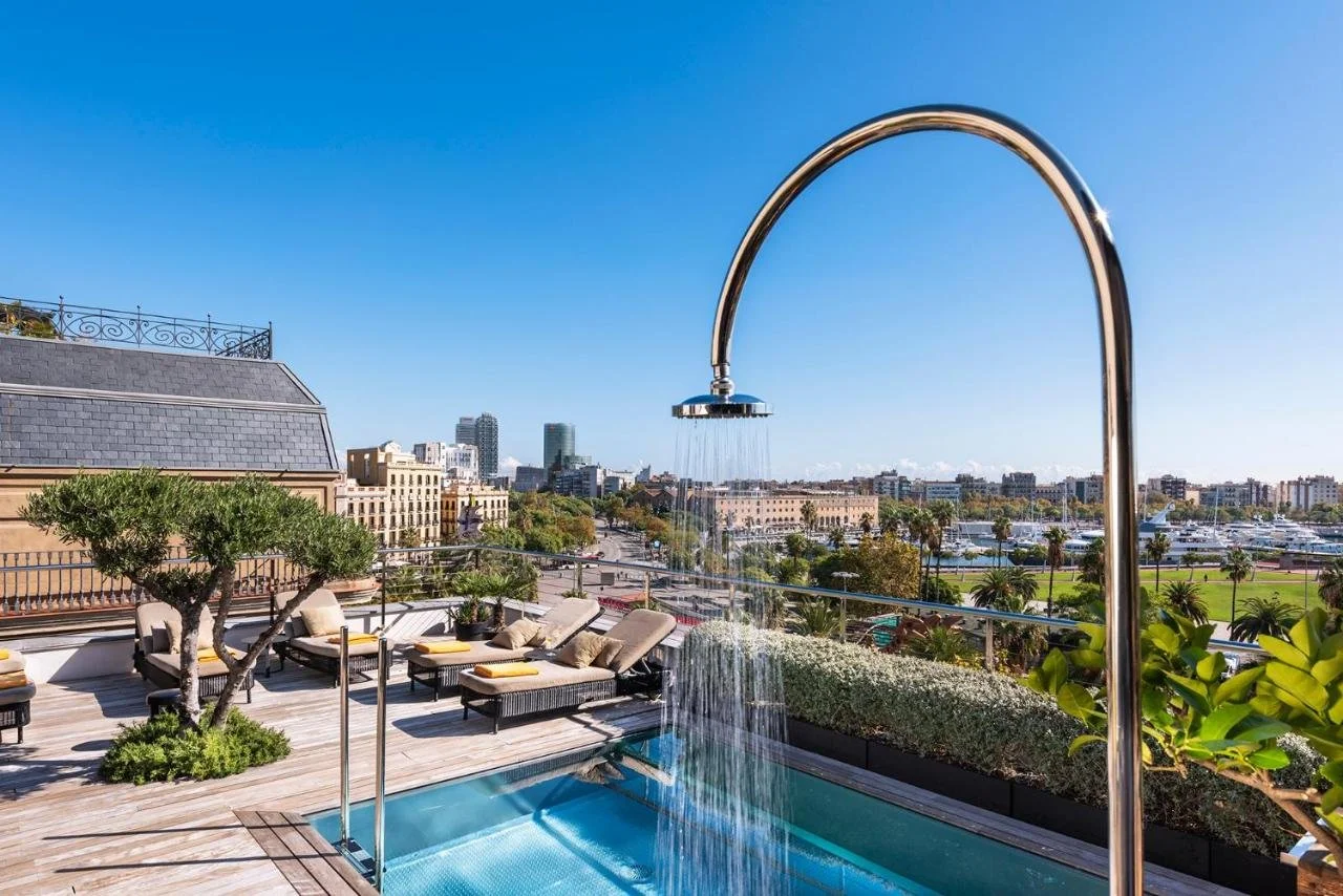 Serras Barcelona rooftop pool terrace with outdoor shower Port Vell marina palm trees and Barceloneta waterfront panorama