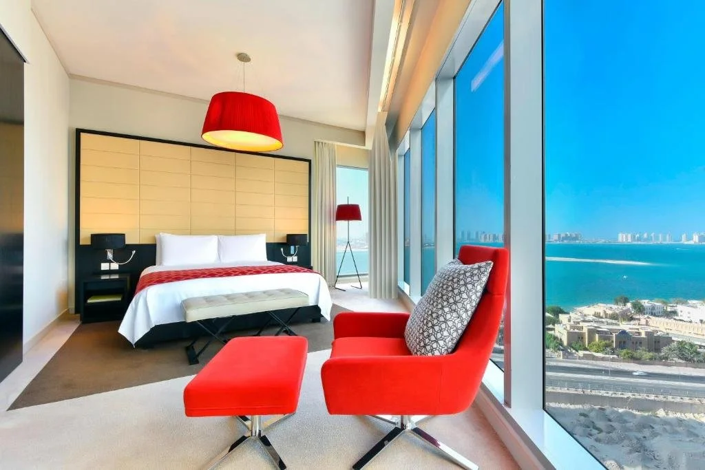 W Doha Doha king room with signature red furnishings and floor-to-ceiling window overlooking the Arabian Gulf and The Pearl-Qatar coastline