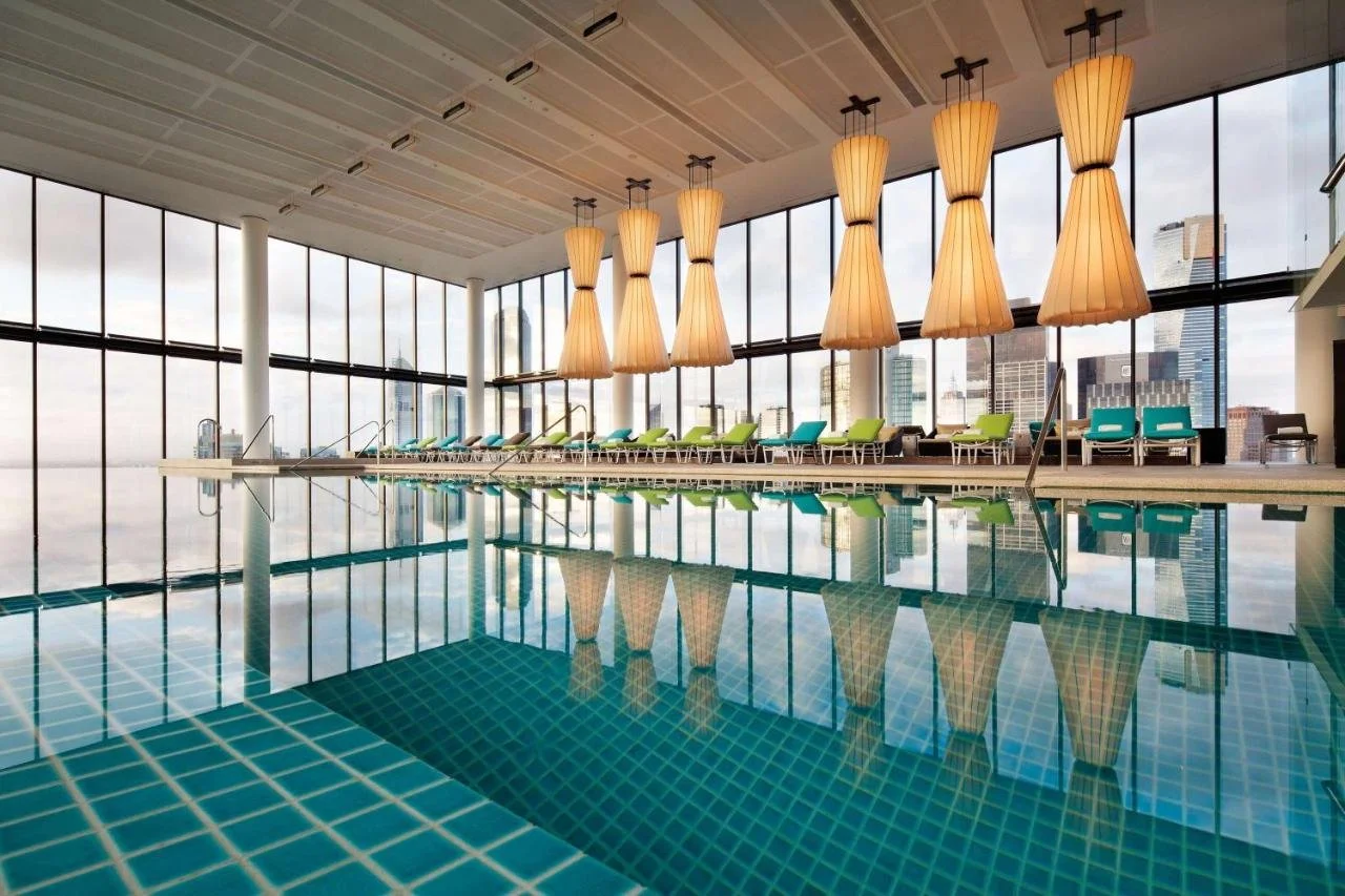 Crown Metropol Melbourne heated indoor pool with pendant lamps and floor-to-ceiling windows facing the Melbourne skyline