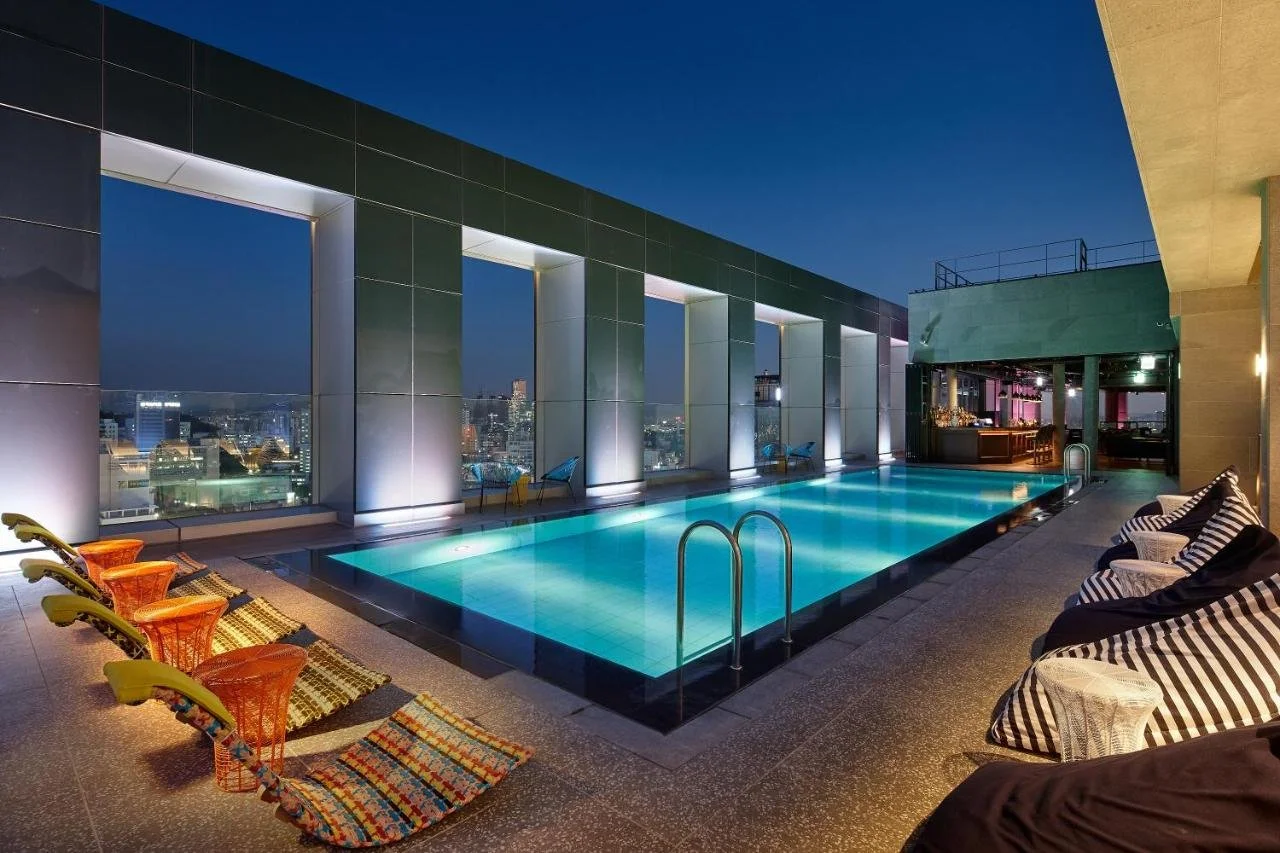 L7 Hongdae by LOTTE Seoul rooftop pool at night with city lights and poolside bar