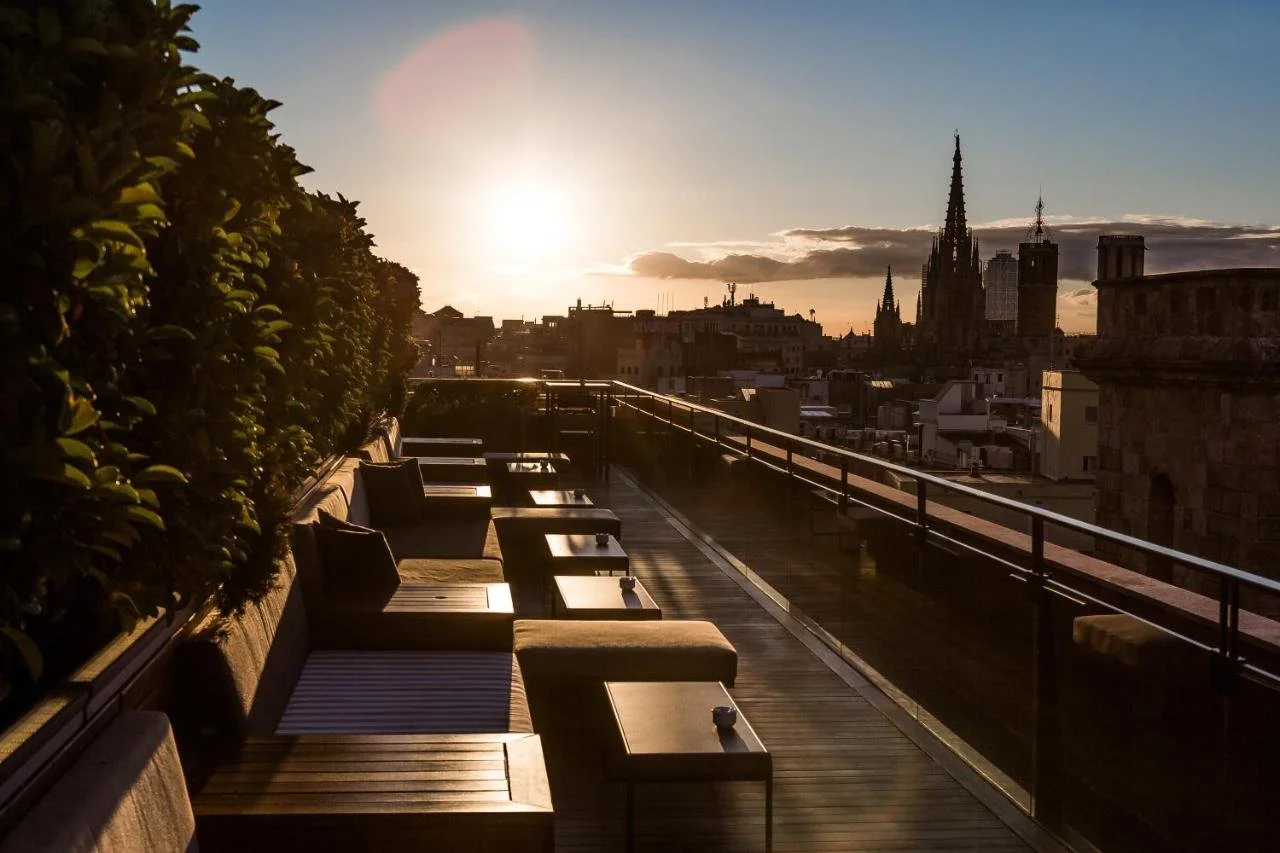 Hotel 1898 Barcelona La Isabela rooftop terrace at sunset with Cathedral of Barcelona spires silhouetted against the golden sky