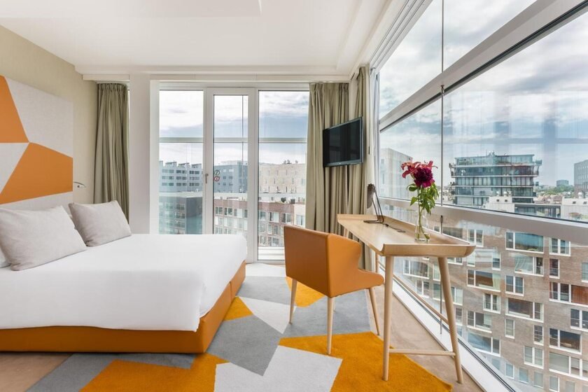 Room Mate Aitana Amsterdam hotel room with floor-to-ceiling glass windows overlooking the Westerdokseiland contemporary waterfront district