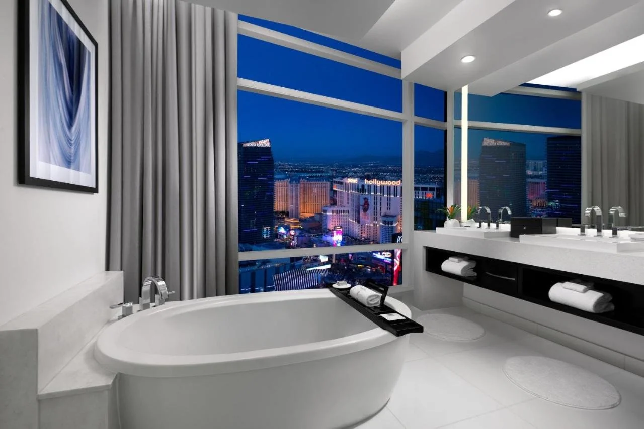 ARIA Resort & Casino Las Vegas bathroom soaking tub with floor-to-ceiling windows overlooking the neon-lit Strip at night
