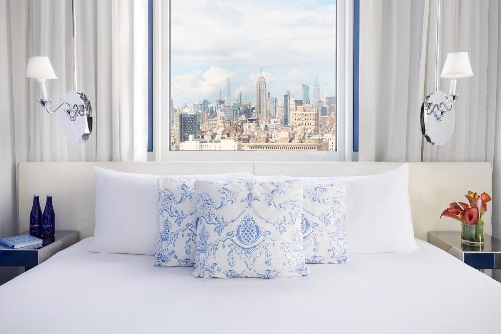 Quarto de hotel com uma janela que retrata a vista do horizonte de Nova York