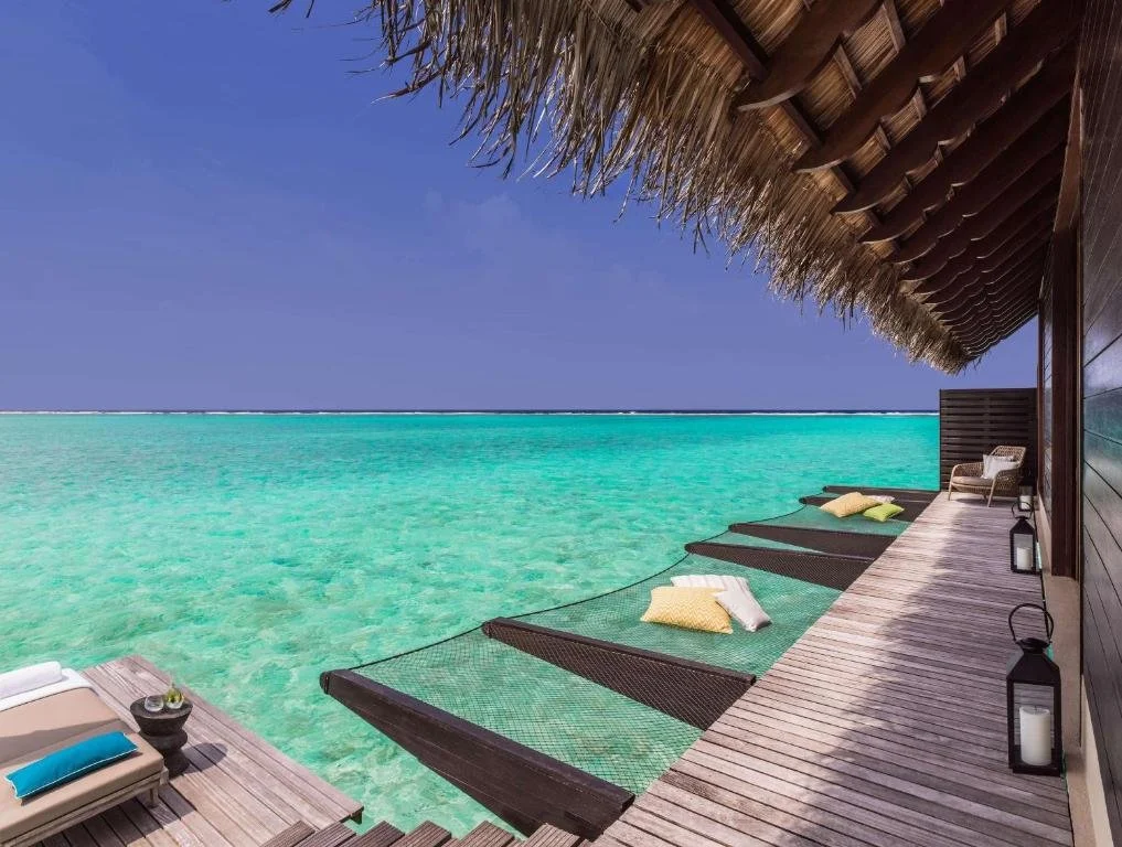 Anantara Kihavah Maldives Villas SEA underwater restaurant interior with panoramic aquarium walls showing reef fish and mirrored ceiling