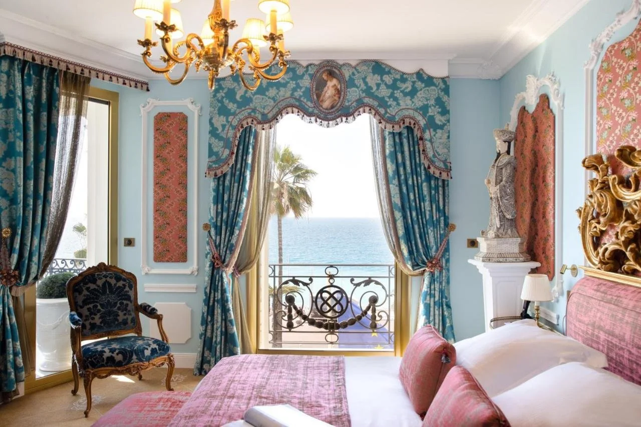 Hotel Le Negresco Nice ornate room with blue floral wallpaper gilded chandelier and sea view through window