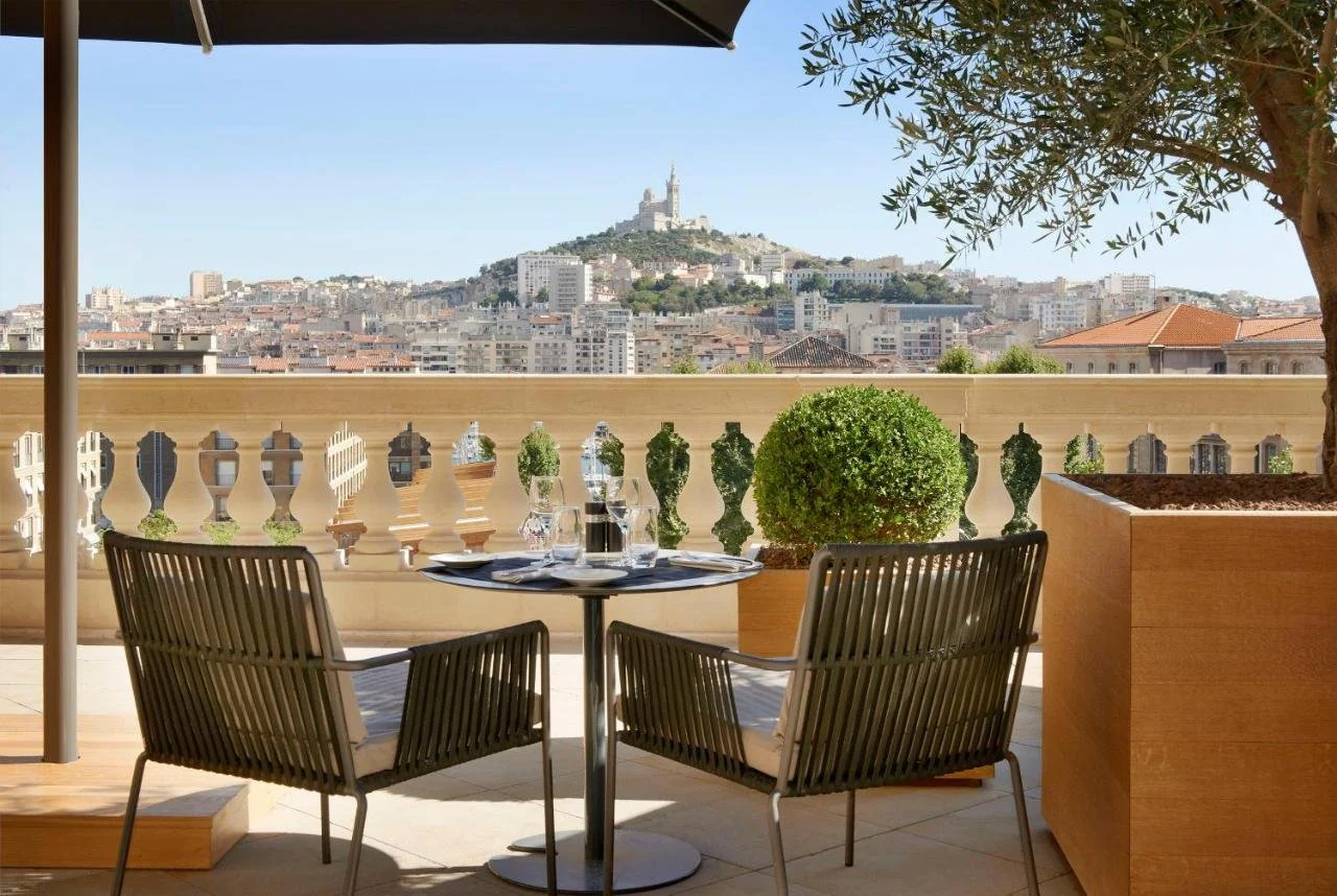 InterContinental Marseille Hotel Dieu terrace dining table with Notre-Dame de la Garde basilica on hilltop in background