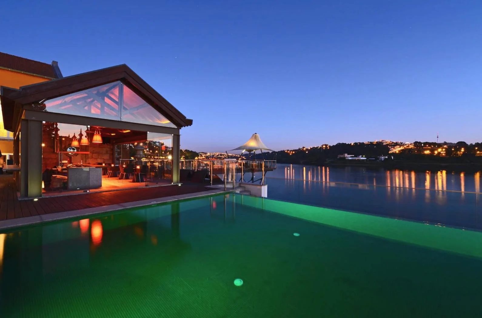 Pestana Palácio do Freixo Porto infinity pool at night overlooking the Douro River with city lights reflected in the water