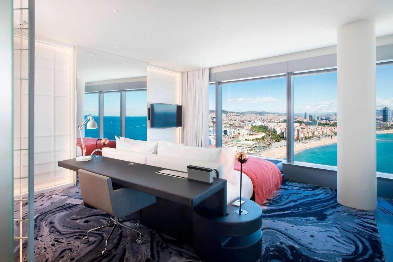 W Barcelona WOW suite with floor-to-ceiling windows showing Barceloneta Beach Mediterranean Sea and Barcelona city skyline with Hotel Arts tower