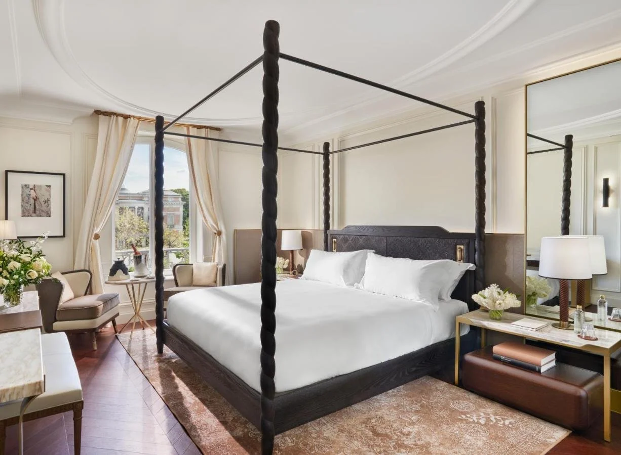Mandarin Oriental Ritz Madrid room with dark four-poster bed and view of the Ritz Garden through tall sash windows