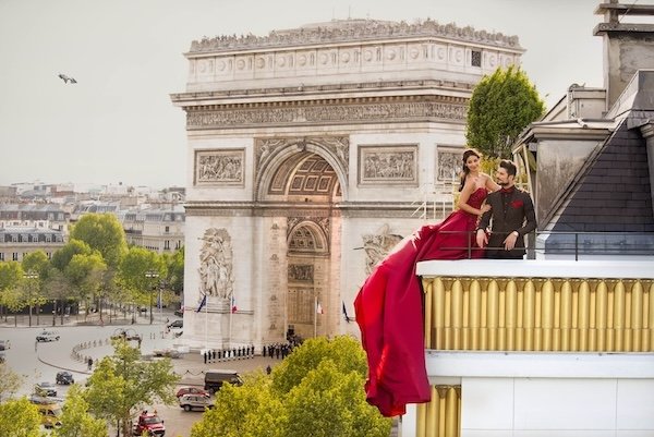 Elegant couple enjoy a romantic moment in a hotel balcony with Arc de Triomphe as backdrop