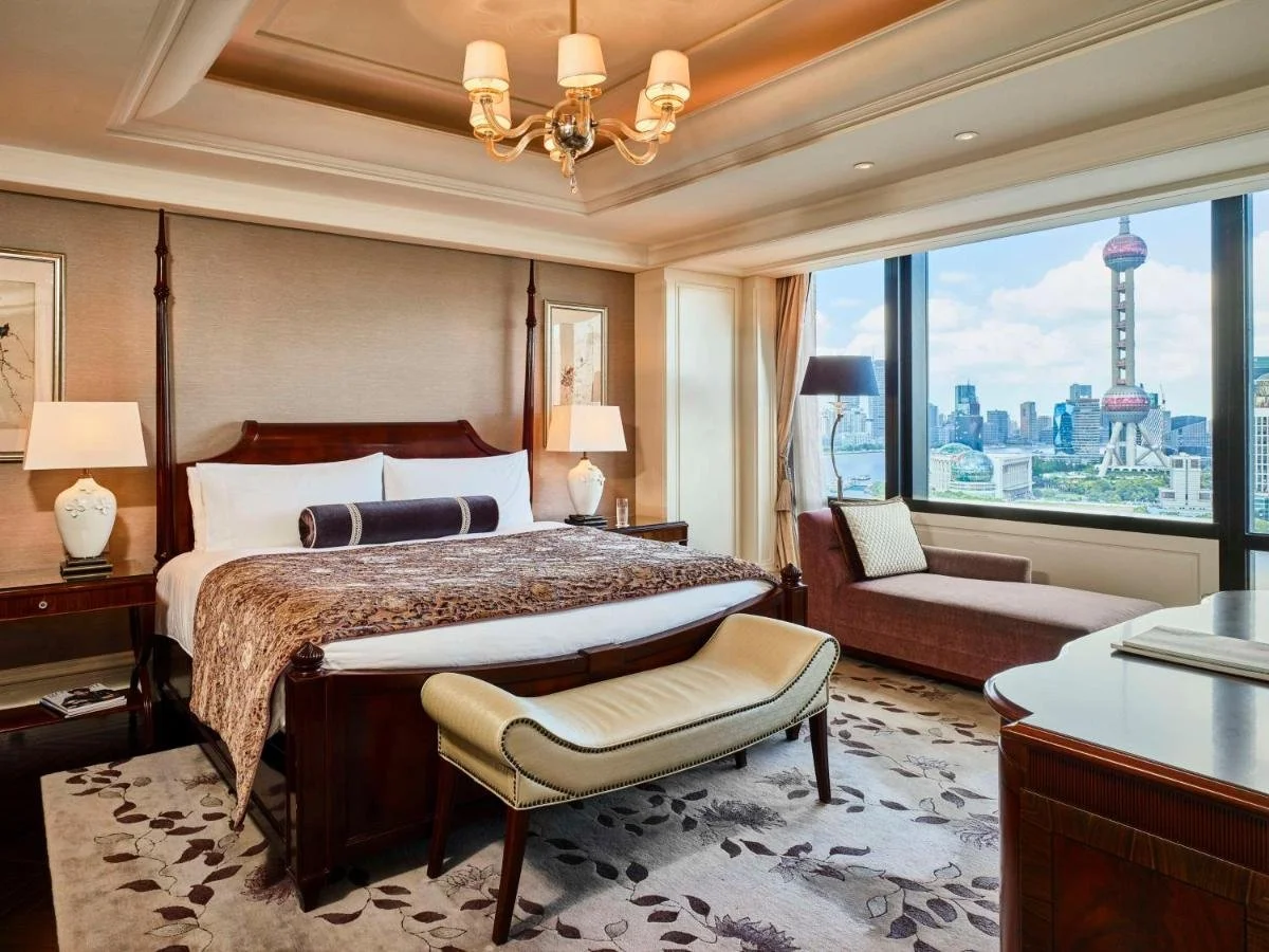 Waldorf Astoria Shanghai on the Bund suite bedroom with mahogany four-poster bed and window view of Oriental Pearl Tower and Pudong skyline