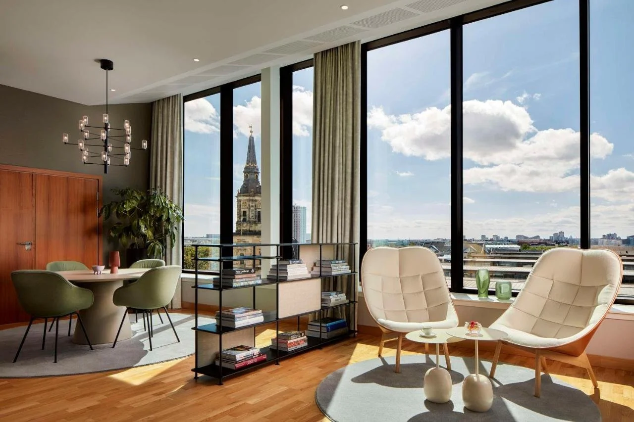 NH Collection Copenhagen suite with floor-to-ceiling windows overlooking church spire, city rooftops, and harbor beyond