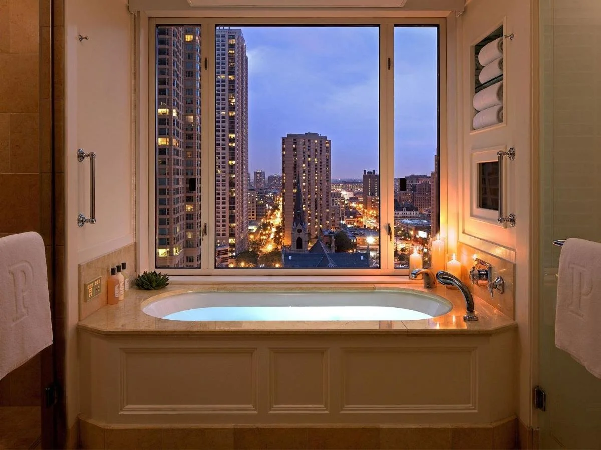The Peninsula Chicago bathtub with candles and romantic mood overlooking Chicago skyline