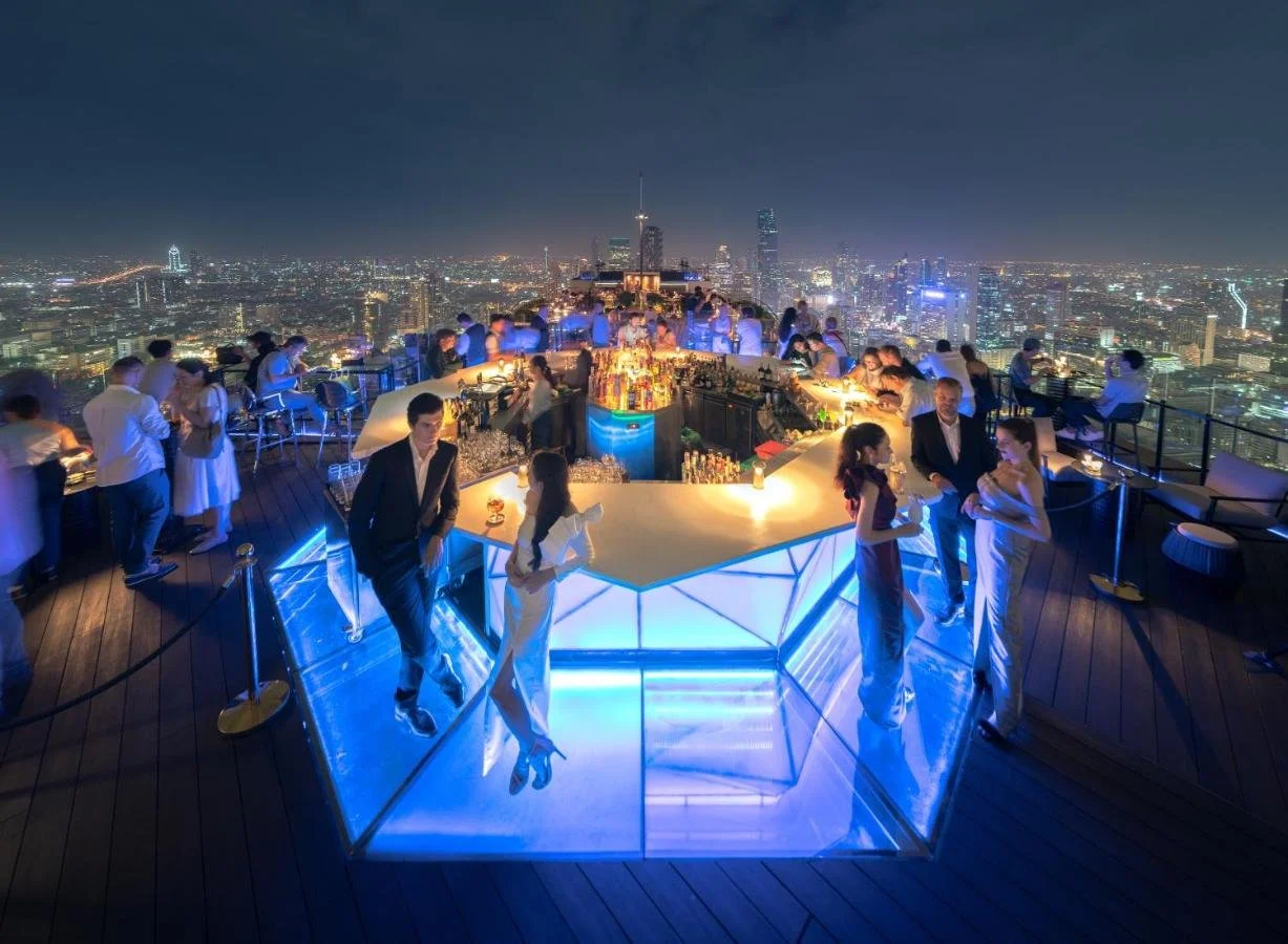 Banyan Tree Bangkok Moon Bar open-air rooftop bar at night with illuminated blue counter and 360-degree Bangkok city skyline