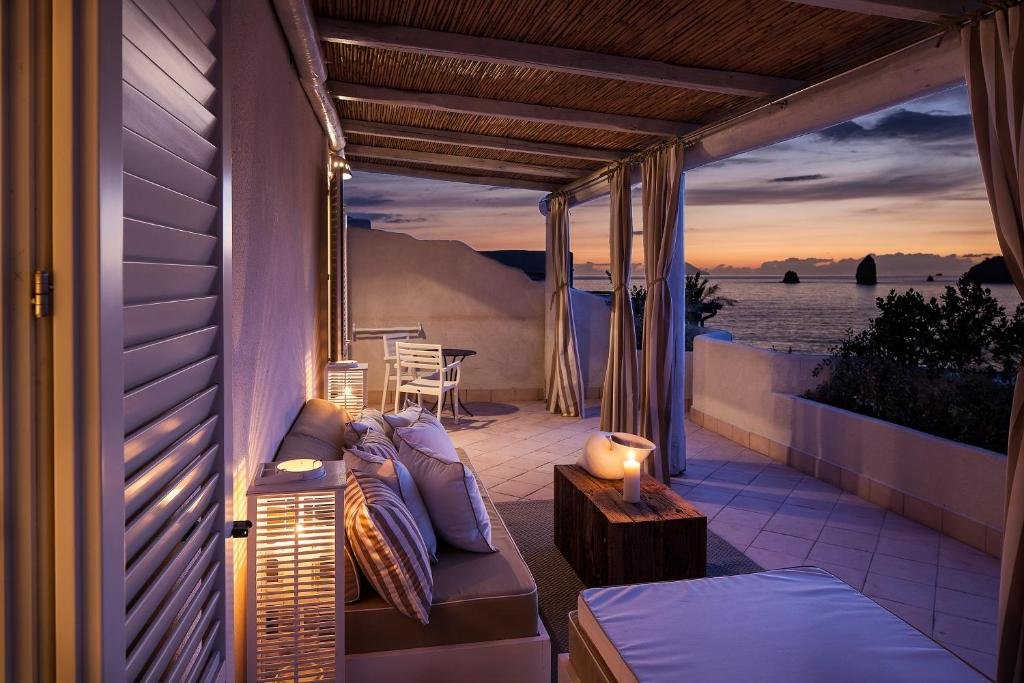 Therasia Resort Vulcano covered terrace lounge at sunset with volcanic sea stack