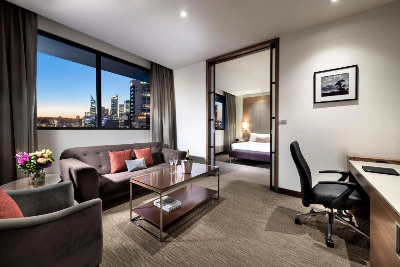 Pan Pacific Perth two-room suite at dusk with Perth CBD skyline visible through living room window