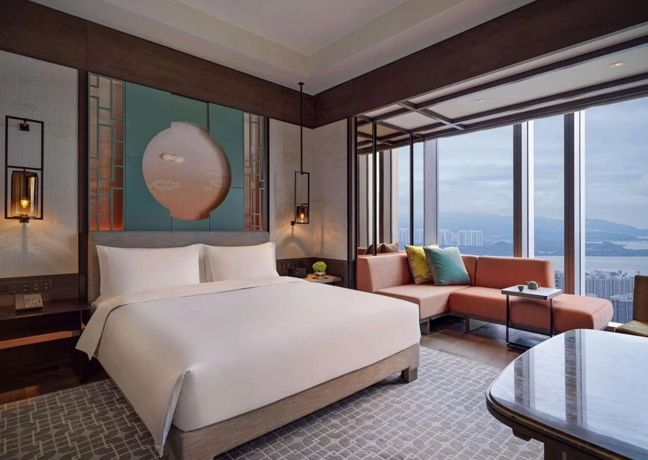 Park Hyatt Shenzhen suite with Chinese-influenced wall art and floor-to-ceiling corner windows overlooking Shenzhen Bay toward the hills of Hong Kong