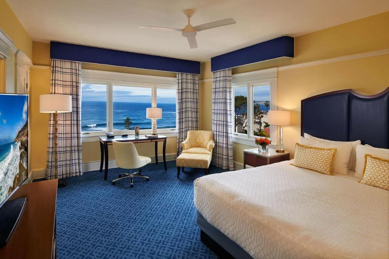 Grande Colonial La Jolla hotel room with Pacific Ocean view through two windows and classic blue and gold decor