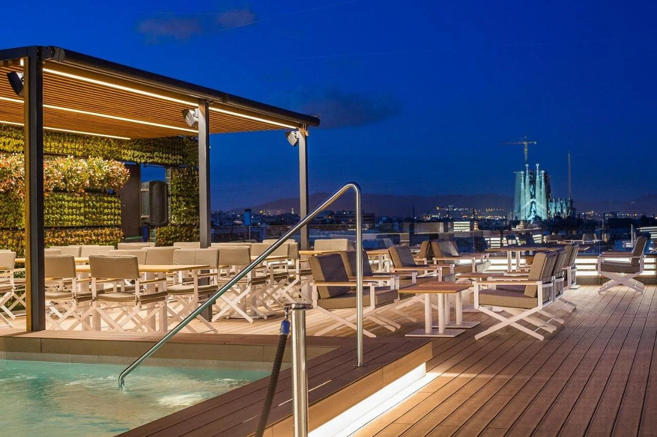 Majestic Hotel Spa Barcelona GL rooftop pool deck at night with illuminated Sagrada Família towers visible in the distance
