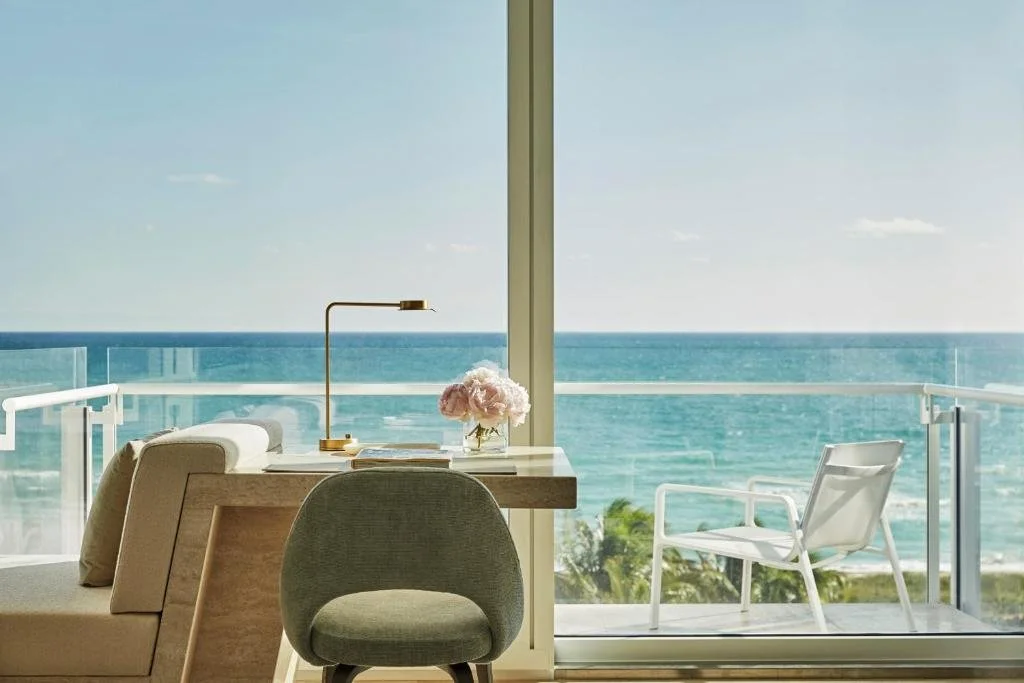 Four Seasons Hotel at The Surf Club Surfside guest room desk with ocean lamp and peonies, balcony with direct Atlantic Ocean view