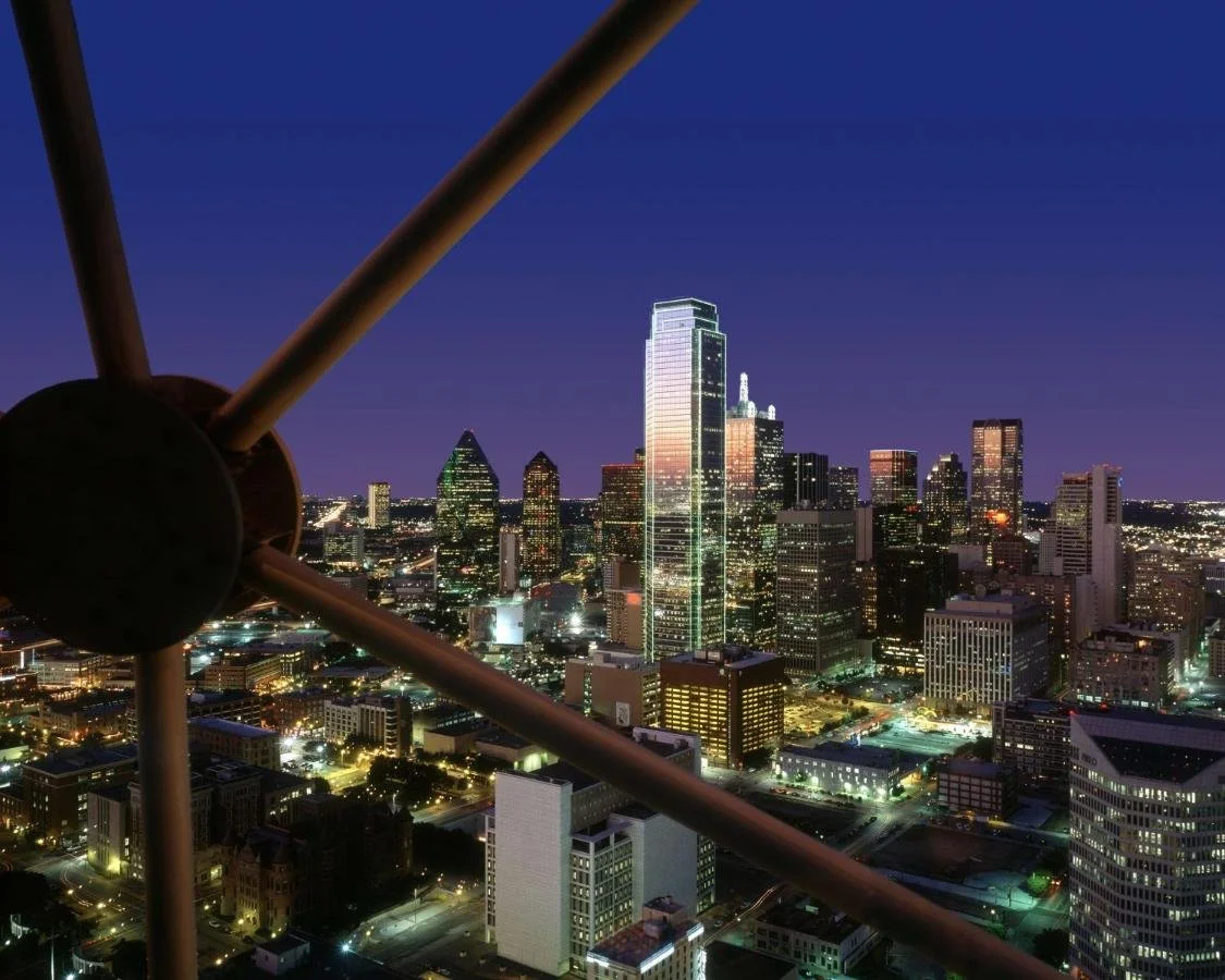 Hyatt Regency Dallas nighttime view of downtown skyline framed by Reunion Tower lattice structure, with Fountain Place and city lights spread below