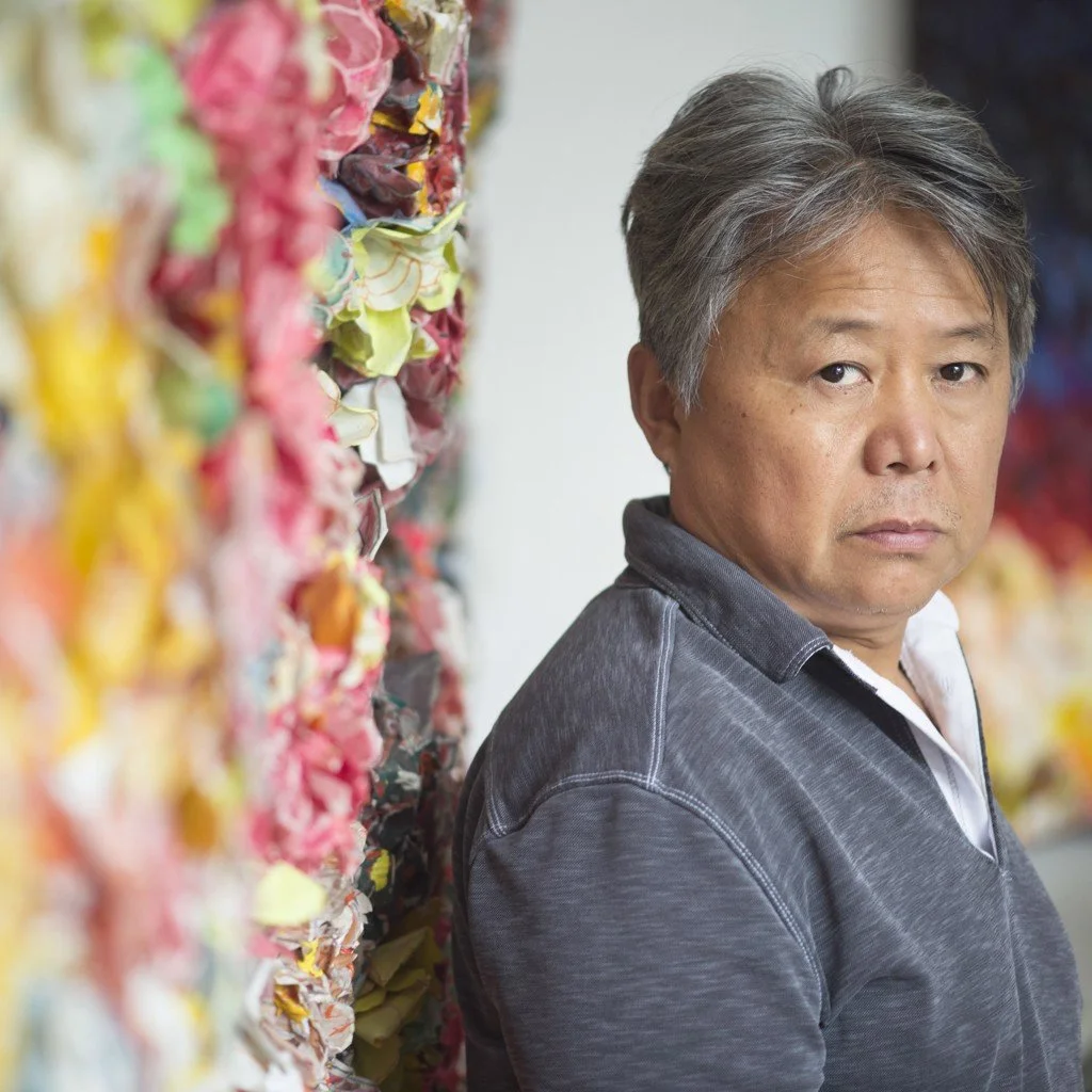 A person standing next to a colorful, abstract art installation, looking towards the camera.