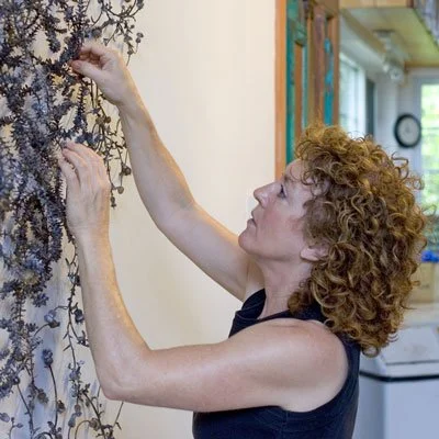 Person arranging intricate wire sculpture on wall