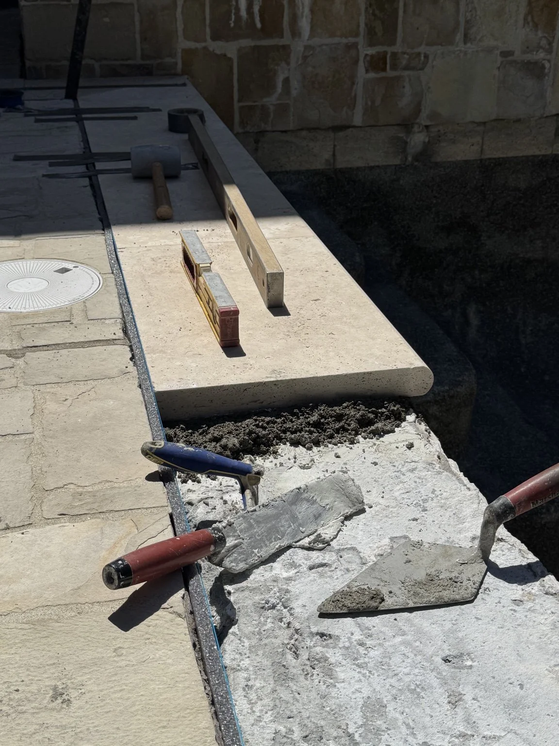 Ivory natural-stone travertine pool coping installation with precision leveling
