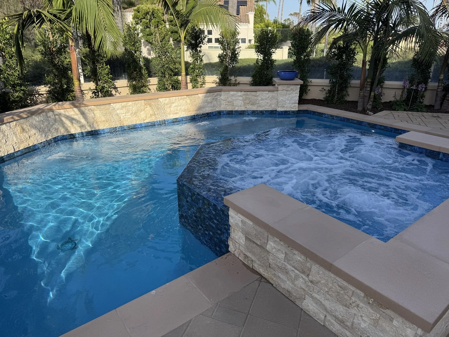 Finished swimming pool and raised spa remodel with new tile, coping, and water features