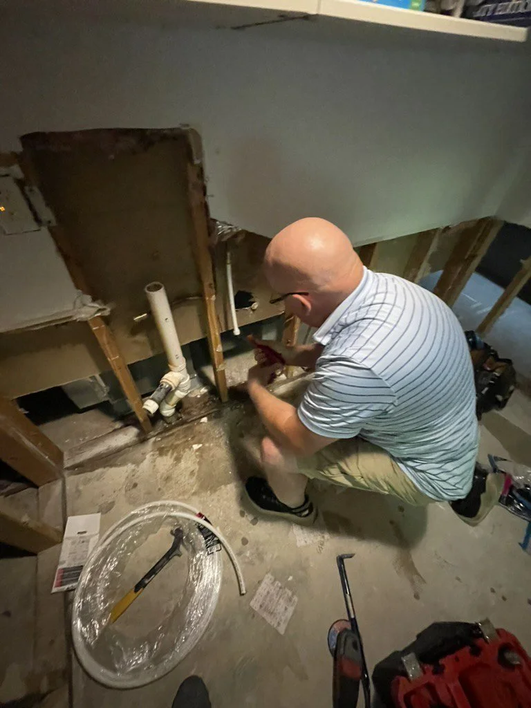 Plumber repairing exposed bathroom plumbing beneath a sink or bathtub.