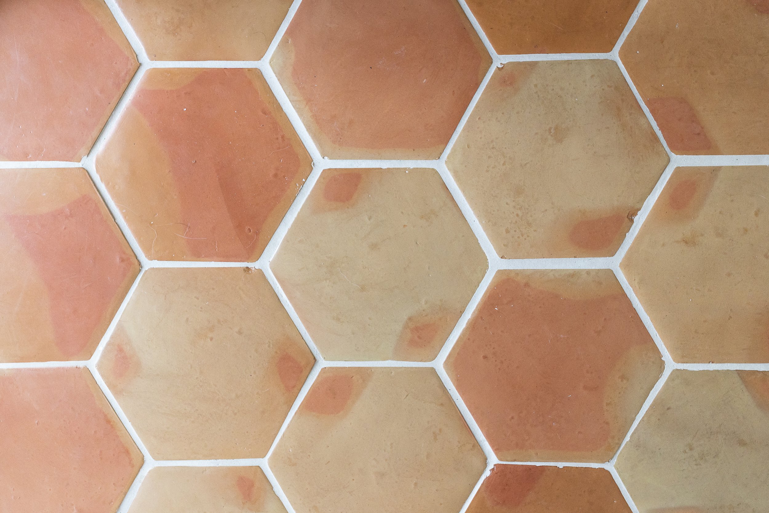 Hexagonal terracotta floor tiles with a textured surface and variations in color.