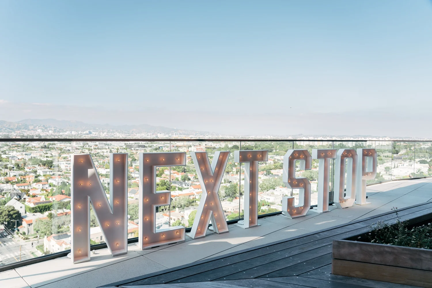 The Next Stop marquee letters on a Los Angeles rooftop overlooking the city