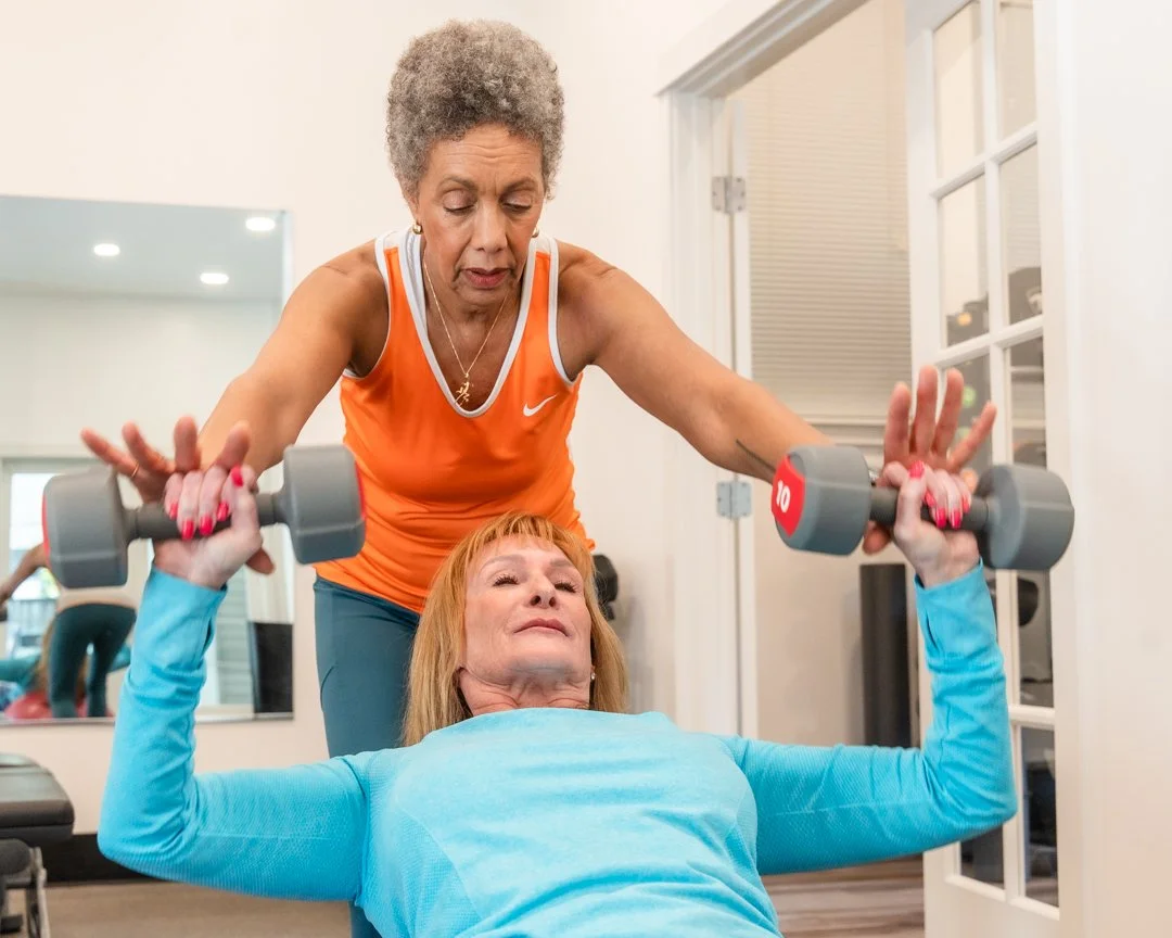 Trainer helping her client with barbells